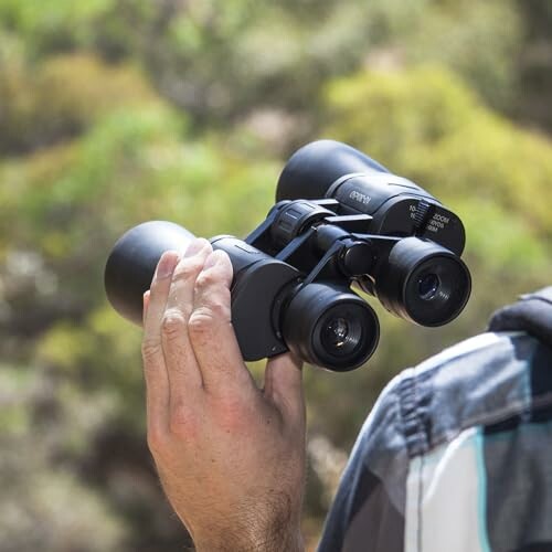 Person holding binoculars outdoors